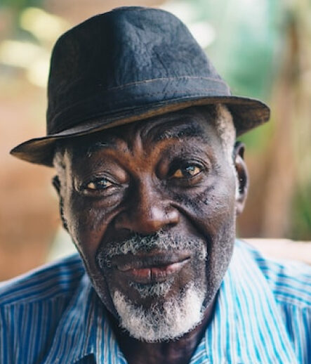 An elderly man smiling in a hat