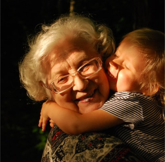 An alderly woman being hugged by her grandchild
