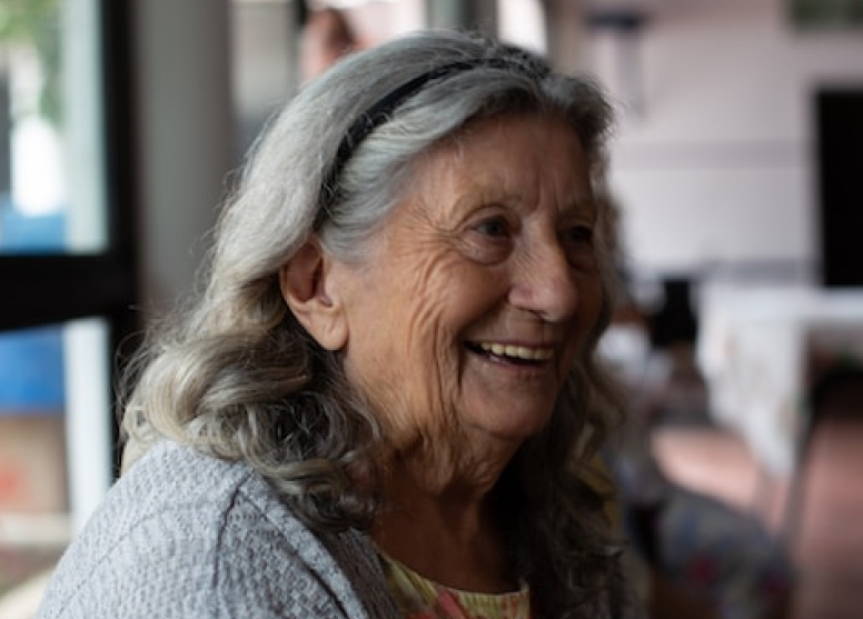 An elderly woman smiling in a restaurant
