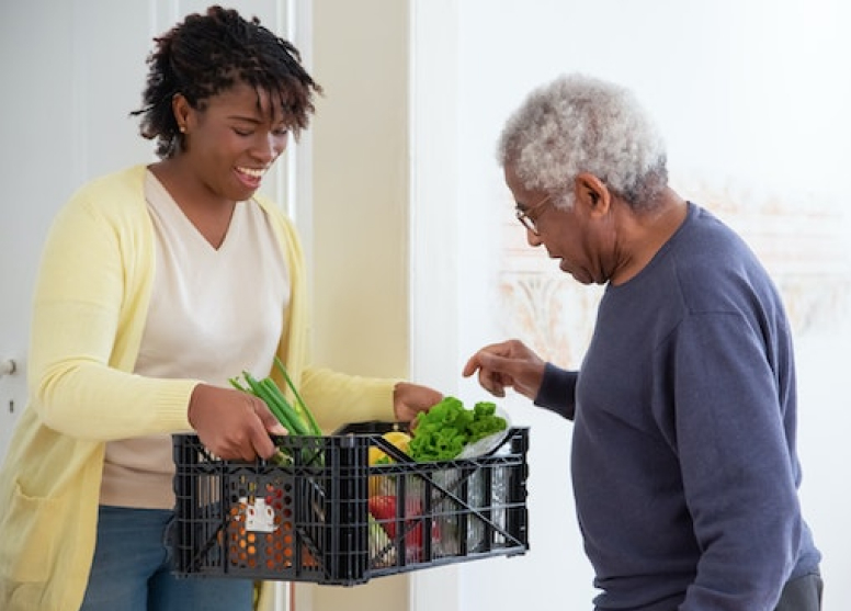 An aged care worker bringing groceries to an elderly man